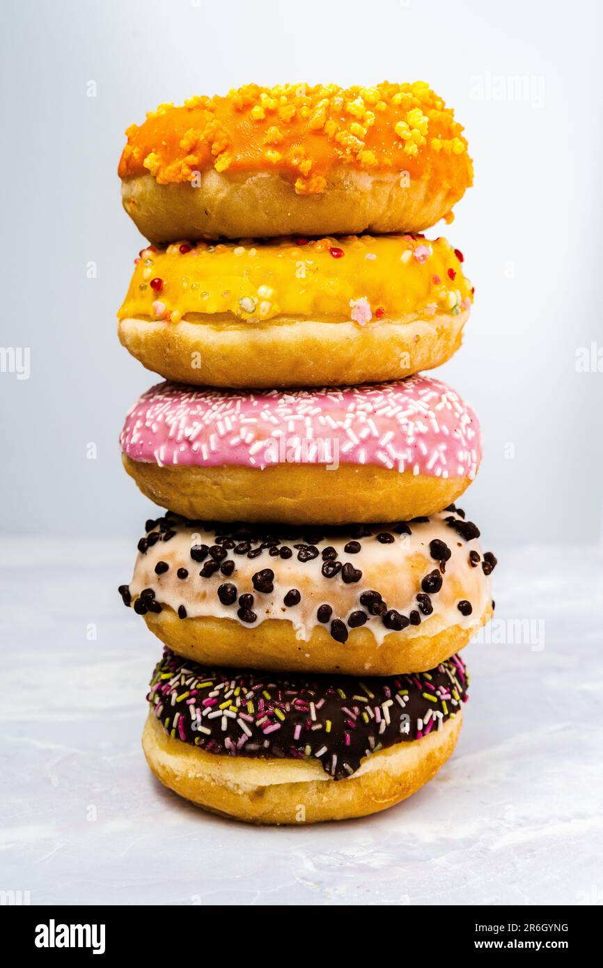 A variety of colorful donuts arranged on a table against a white ...