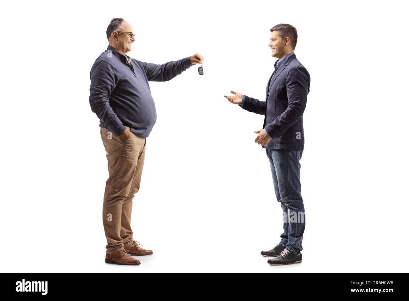 Mature man handing car keys to a younger man isolated on white background Stock Photo