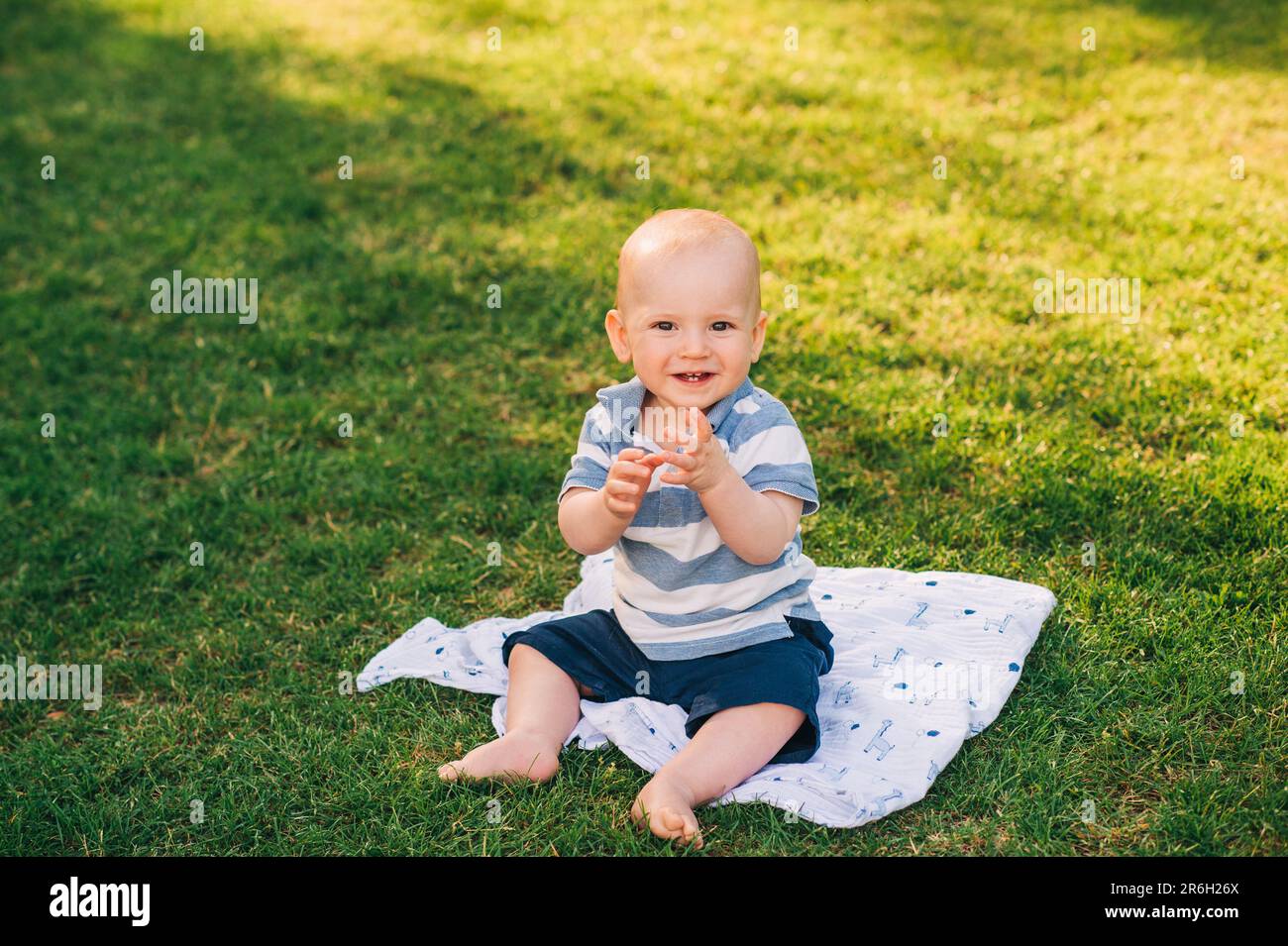 Outdoor portrait of adorable laughing baby boy playing in summer parc ...