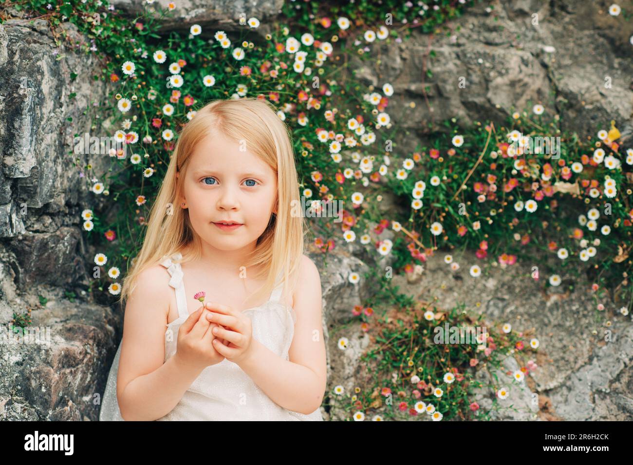 Outdoor summer portrait of adorable 5 year old little girl playing with  daisy flowers Stock Photo - Alamy