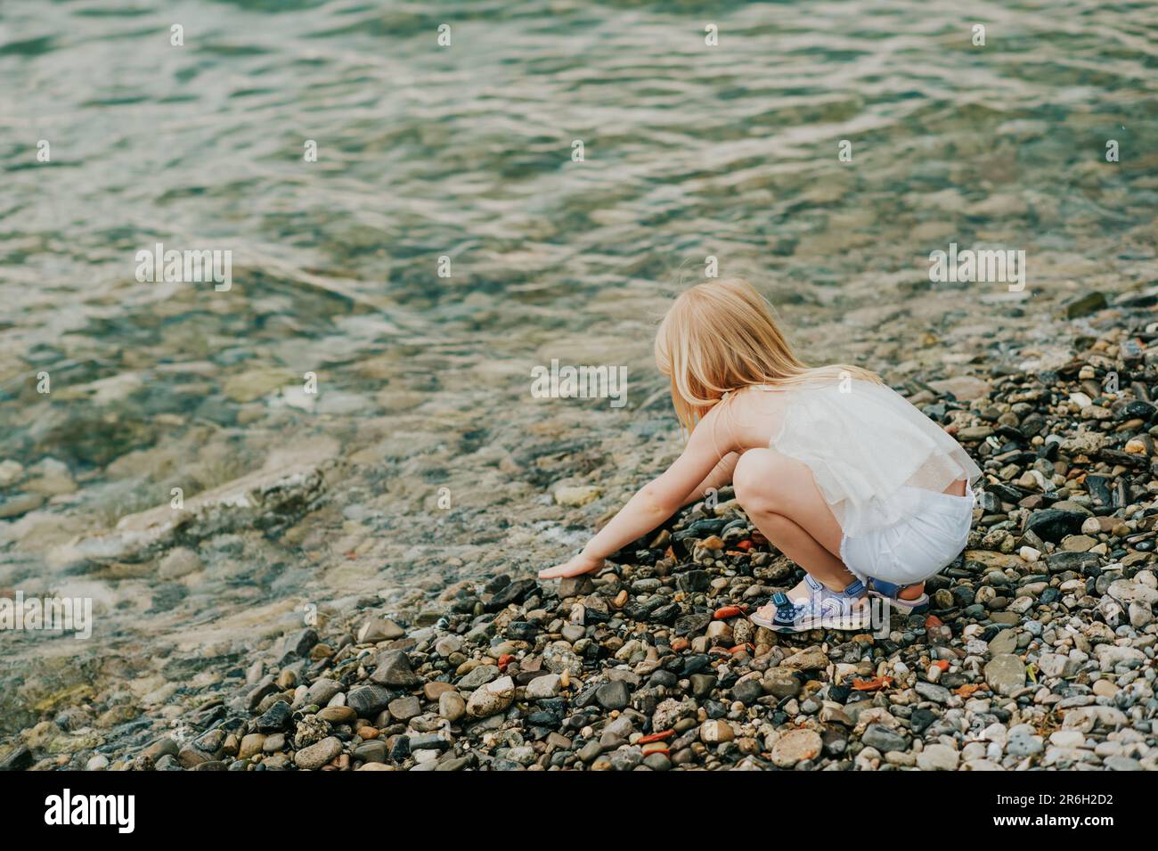 Child playing by the lake in summer, back view Stock Photo