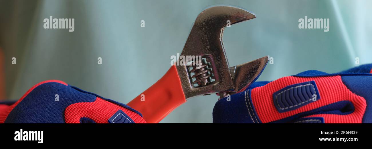 Person hands in protective work gloves holding spanner. Stock Photo