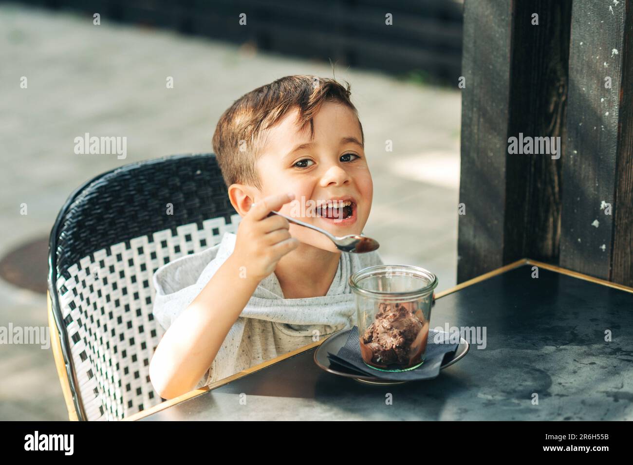 Happy little boy eating chocolate ice cream in outdoor cafe Stock Photo