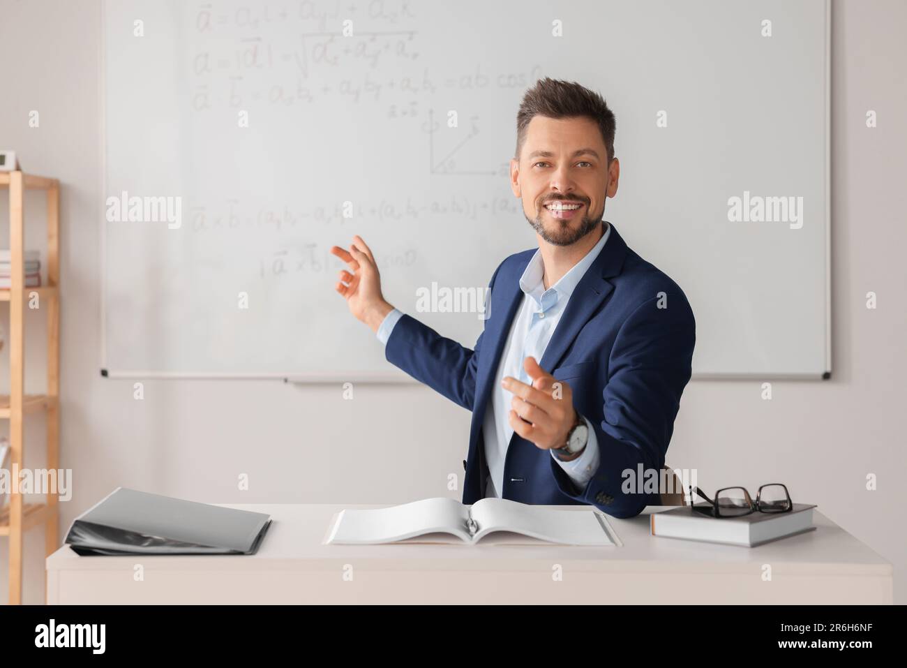 Happy teacher explaining mathematics at table in classroom Stock Photo ...