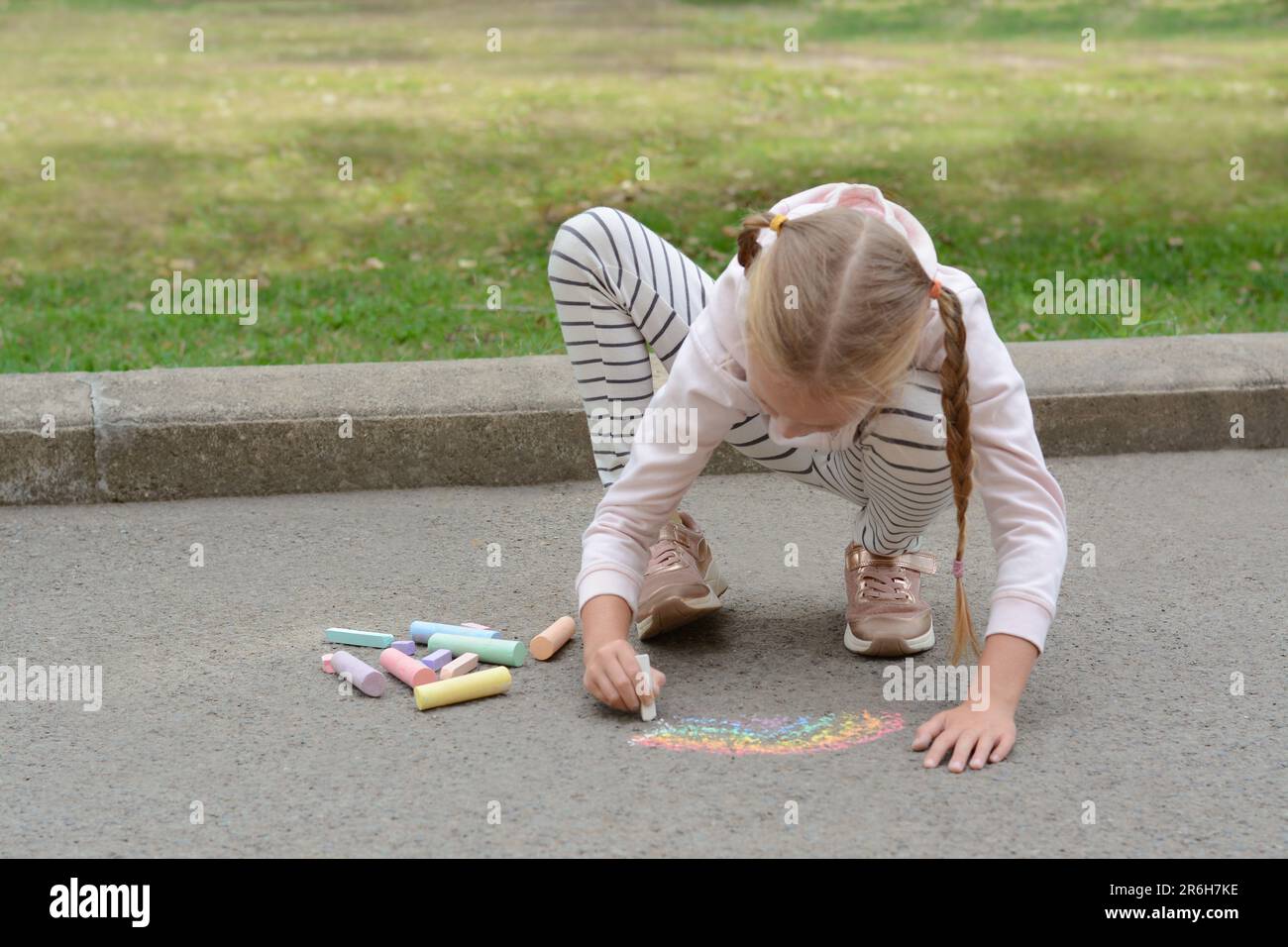 Little child drawing rainbow with chalk on asphalt Stock Photo - Alamy