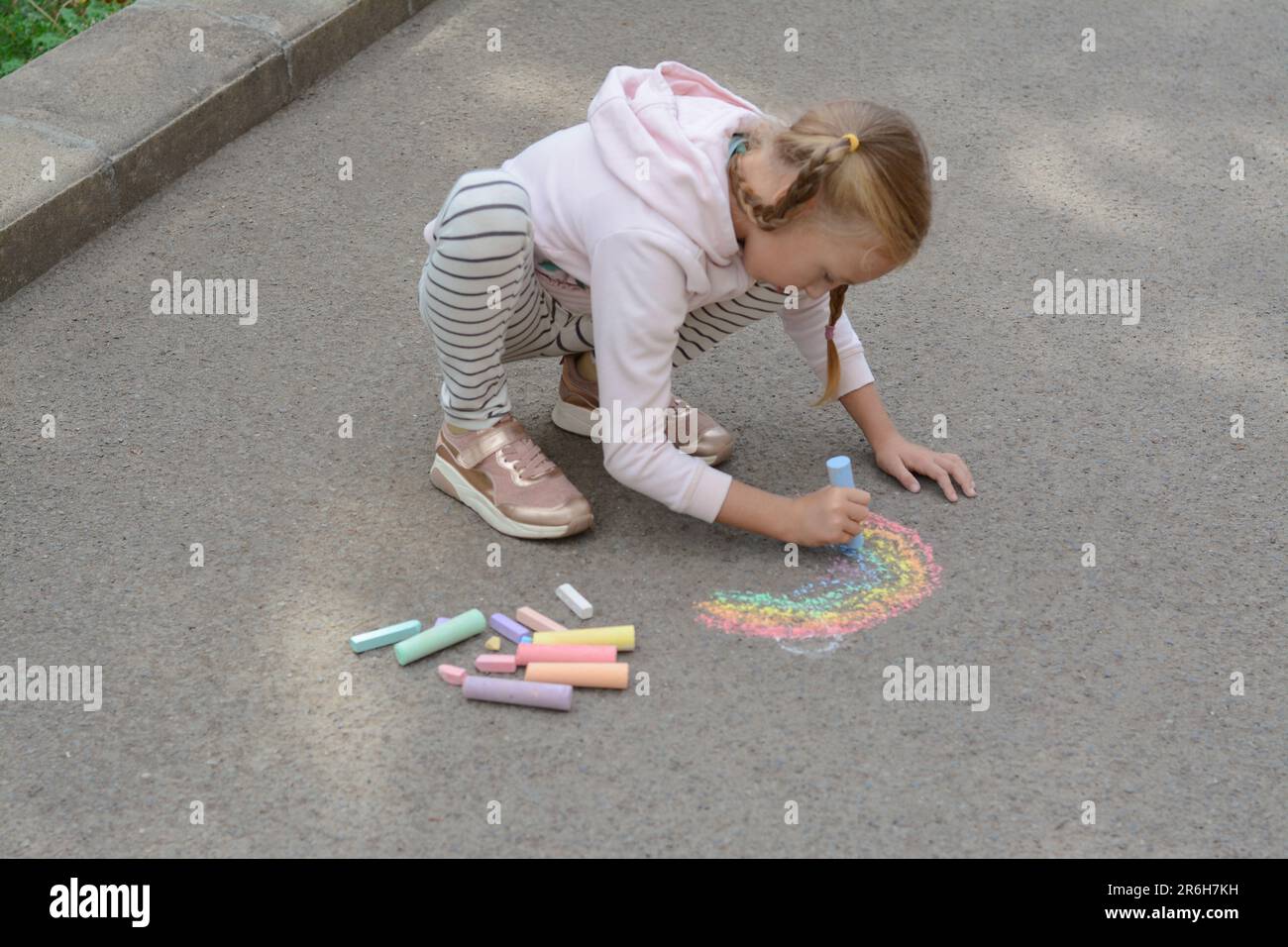 Little child drawing rainbow with chalk on asphalt Stock Photo - Alamy