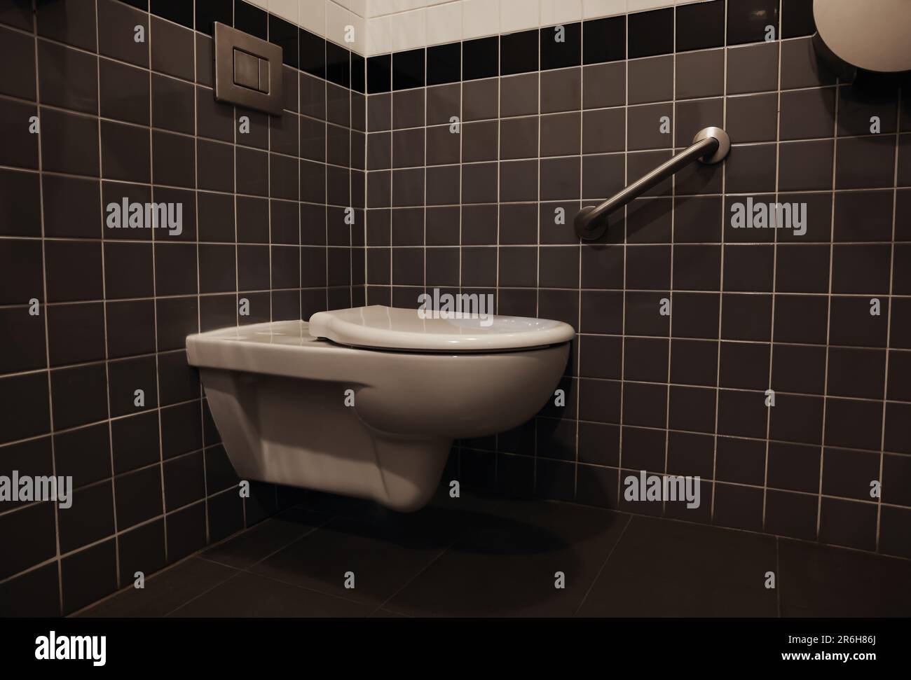 Clean ceramic toilet bowl near tiled wall indoors Stock Photo - Alamy