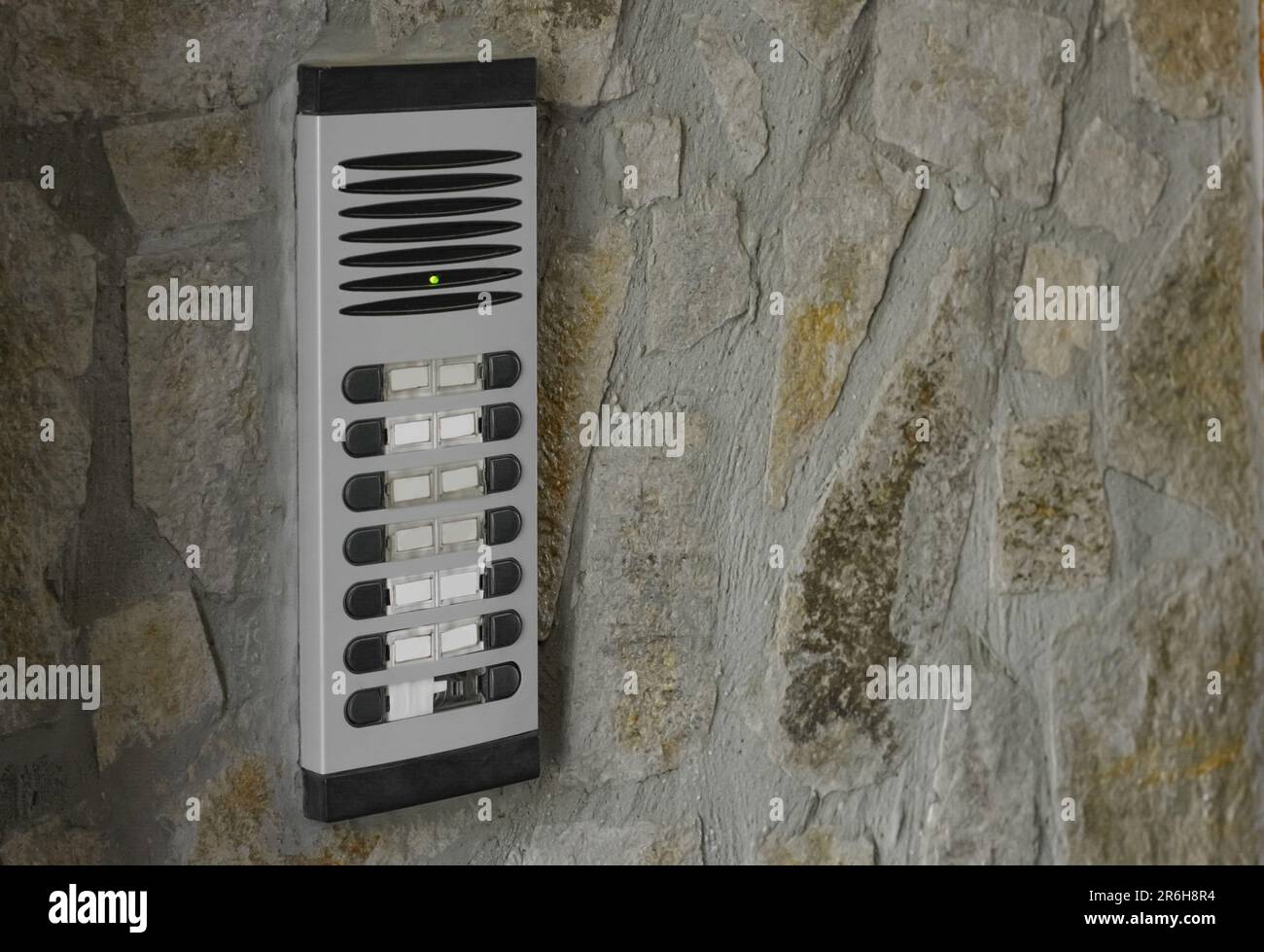 Modern intercom on concrete wall with stone fragments, space for text. Security system Stock Photo