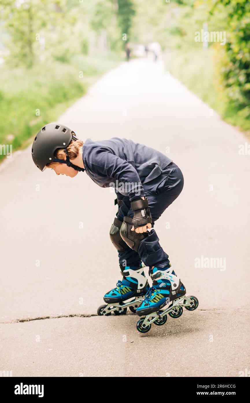 Little boy stuck in asphalt hole, kid falling with rollers Stock Photo