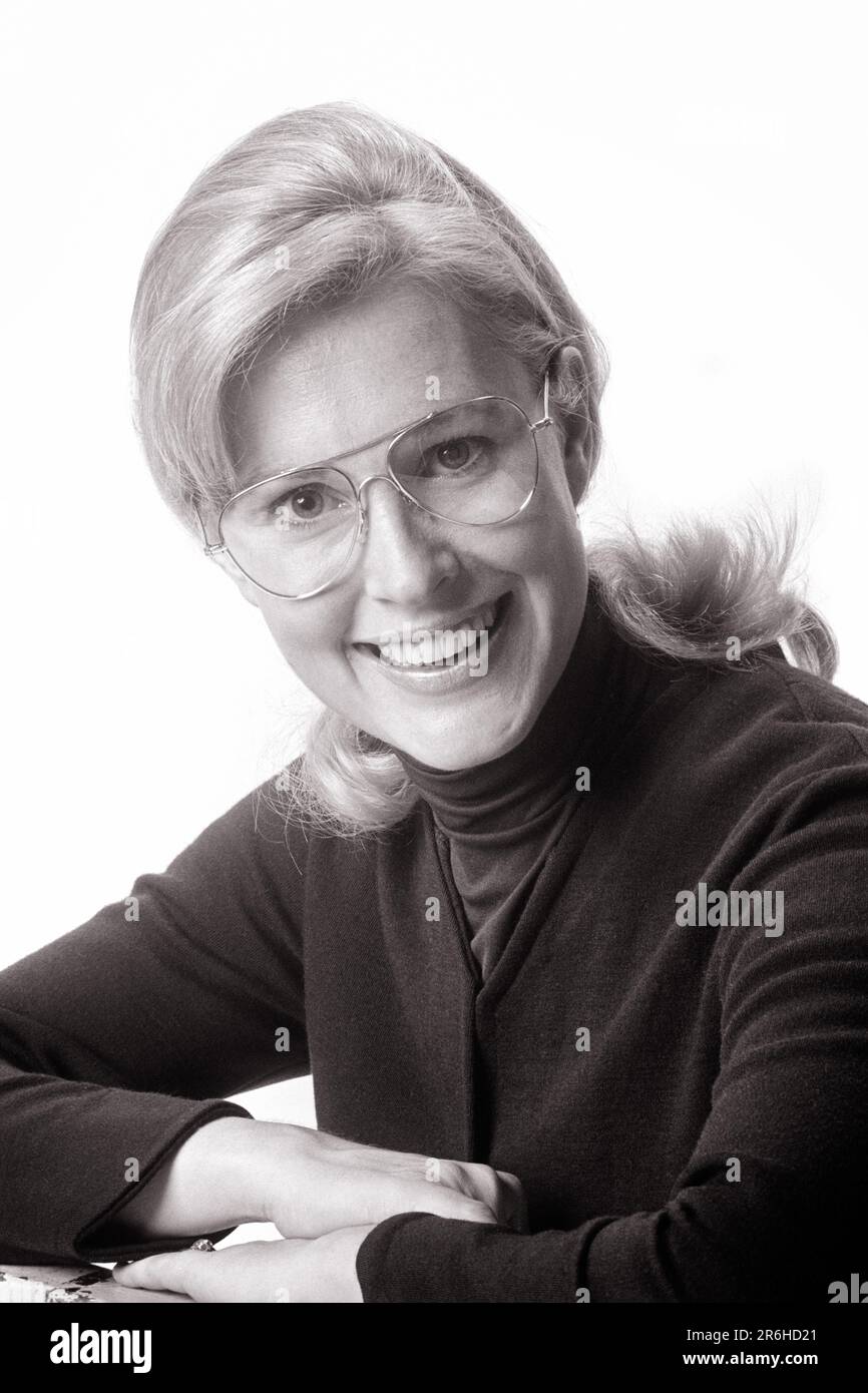 1970s PORTRAIT OF SMILING BLOND WOMAN WEARING AVIATOR STYLE EYEGLASSES RESTING ON FOLDED ARMS LOOKING AT CAMERA - o4120 HAR001 HARS HOME LIFE COPY SPACE LADIES PERSONS CONFIDENCE EYEGLASSES EXPRESSIONS B&W RESTING EYE CONTACT VISION OPTICAL PRETTY HAPPINESS HEAD AND SHOULDERS CHEERFUL SMILES AVIATOR FRIENDLY JOYFUL STYLISH YOUNG ADULT WOMAN BLACK AND WHITE CAUCASIAN ETHNICITY HAR001 OLD FASHIONED Stock Photo