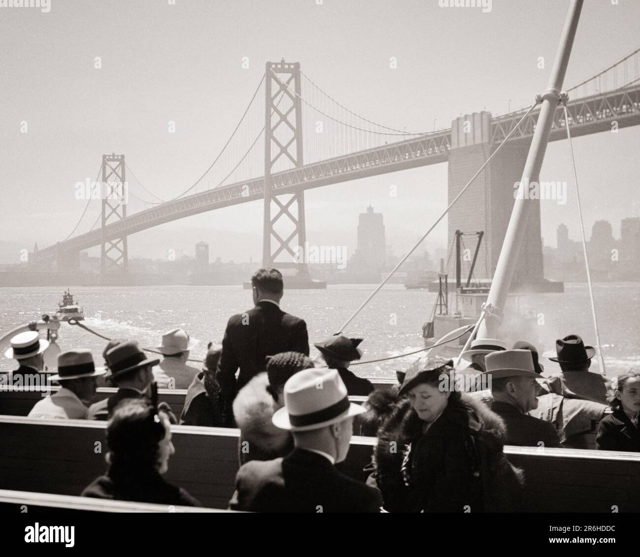 1930s VIEW FROM A FERRY FROM SAN FRANCISCO TO OAKLAND OF THE OAKLAND BAY BRIDGE CALIFORNIA USA - q37264 CPC001 HARS SCENIC MALES TRANSPORTATION B&W FRANCISCO SMOG HEAD AND SHOULDERS ADVENTURE COMMUTERS CA TOURISTS WEST COAST CITIES FERRY OAKLAND STYLISH FERRIES OAKLAND BAY BRIDGE SAN FRANCISCO TRANSIT BLACK AND WHITE CAUCASIAN ETHNICITY OLD FASHIONED SUSPENSION BRIDGE Stock Photo
