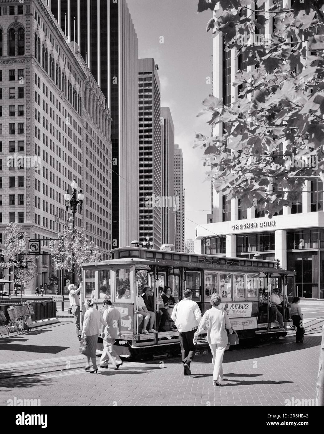 1970s 1980s CABLE CAR TURNAROUND ON MARKET STREET AND POWELL PASSENGERS GETTING ON AND OFF SAN FRANCISCO CA USA - r25638 KRU001 HARS PASSENGERS UNITED STATES COPY SPACE FULL-LENGTH LADIES ICON PERSONS UNITED STATES OF AMERICA MALES BUILDINGS SYMBOLS TRANSPORTATION B&W FRANCISCO NORTH AMERICA NORTH AMERICAN TIME OFF HIGH ANGLE PROPERTY TRIP AND GETAWAY CA HOLIDAYS REAL ESTATE CONCEPT WEST COAST CONCEPTUAL STRUCTURES CABLE CAR EDIFICE SYMBOLIC CONCEPTS POWELL TRANSIT USDA VACATIONS BLACK AND WHITE CABLE CAUCASIAN ETHNICITY ICONIC OLD FASHIONED PUBLIC TRANSPORTATION REPRESENTATION Stock Photo