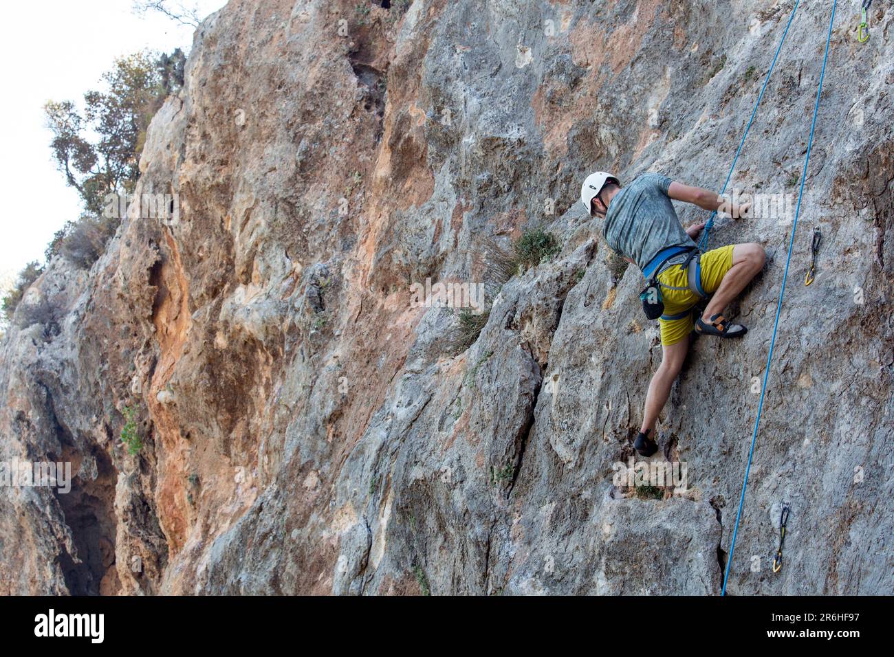 A climber conquers a challenging rock face with skill and determination. Stock Photo