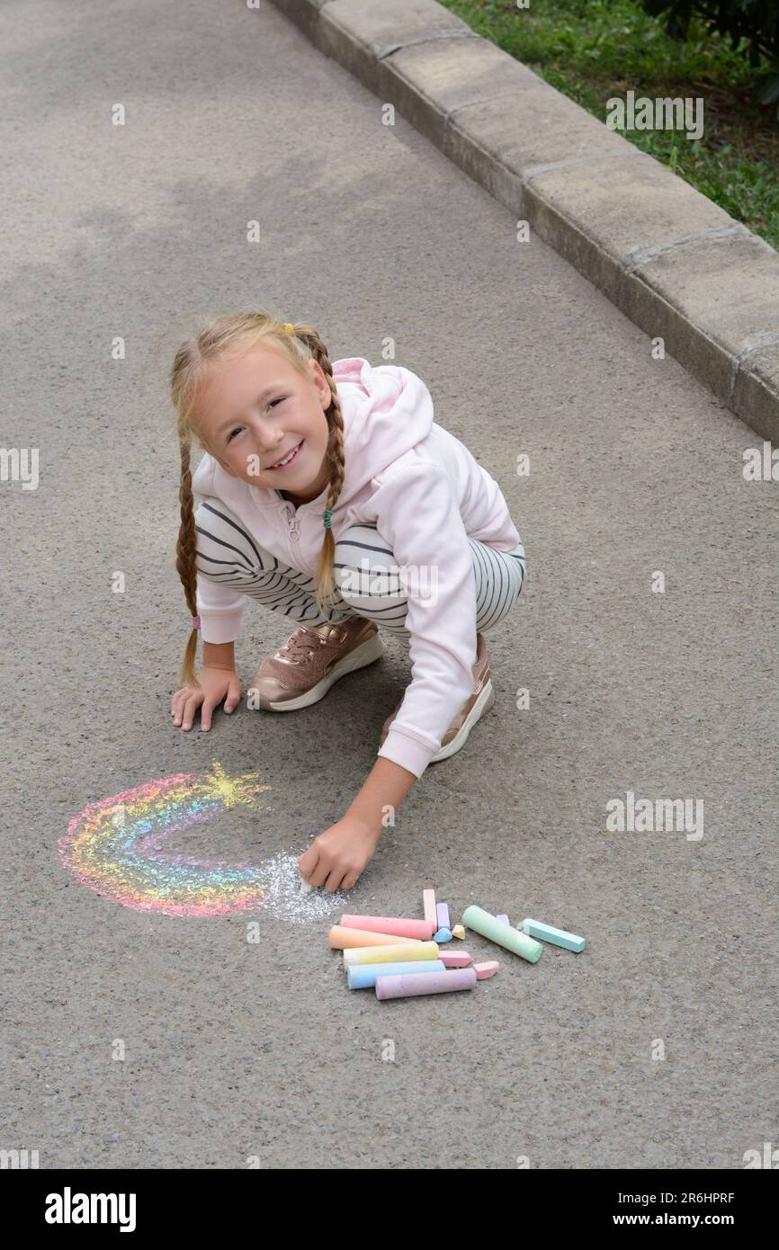 Little child drawing rainbow with chalk on asphalt Stock Photo - Alamy