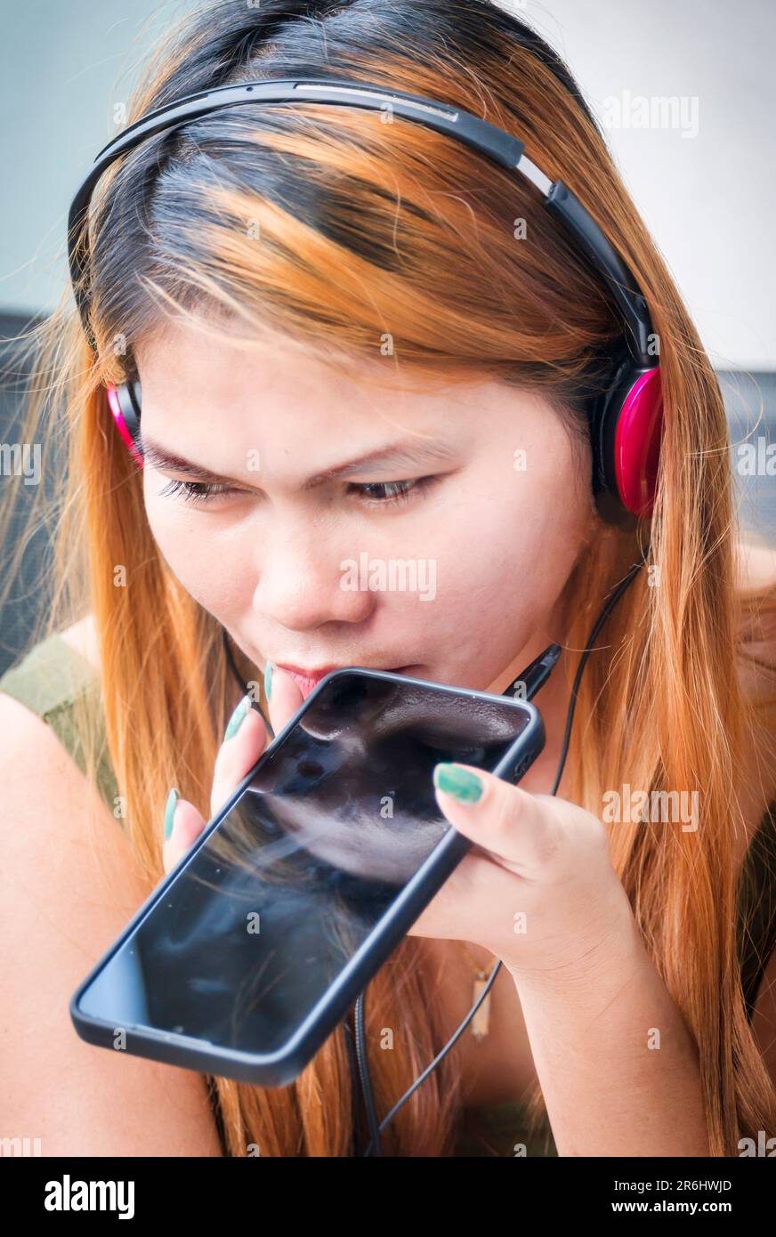 Sitting outside, on a high rise condo building balcony,wearing headphones,speaking to her family