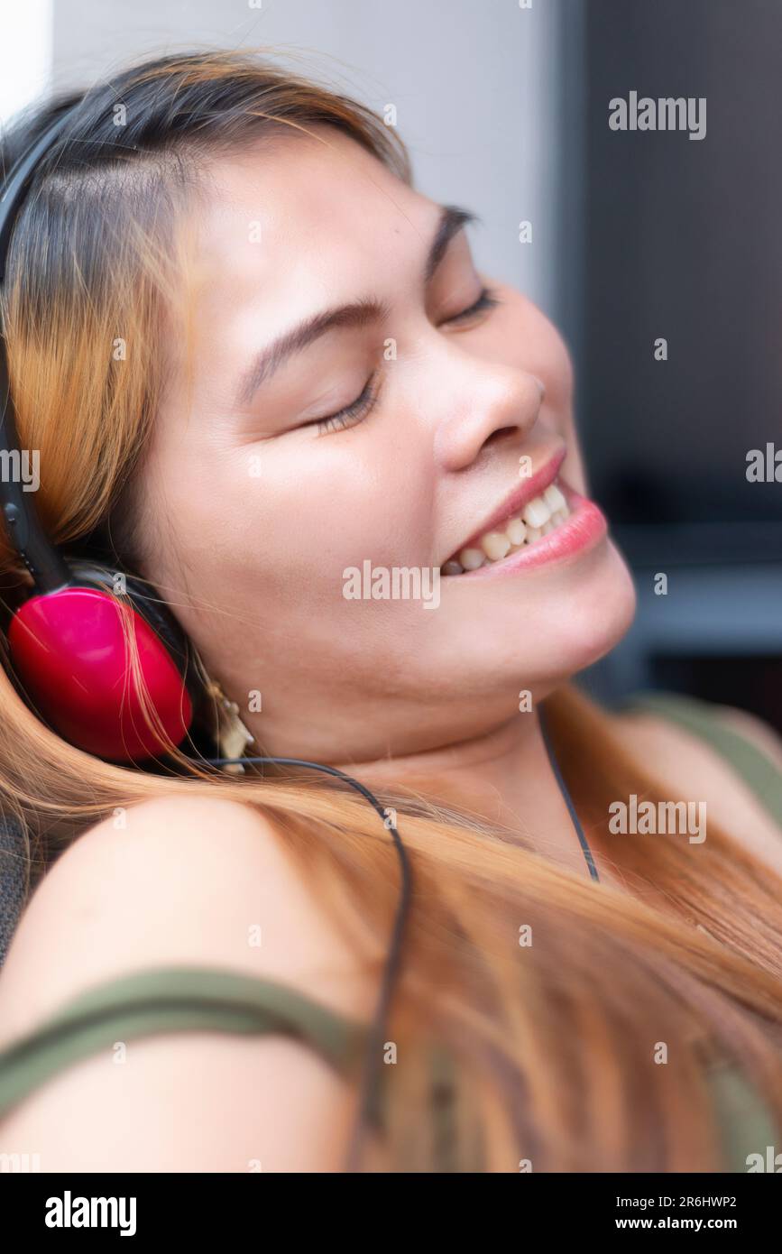 Sitting outside, on a modern high rise condo building balcony,wearing headphones,speaking long distance to her family who live in a remote part of rur Stock Photo
