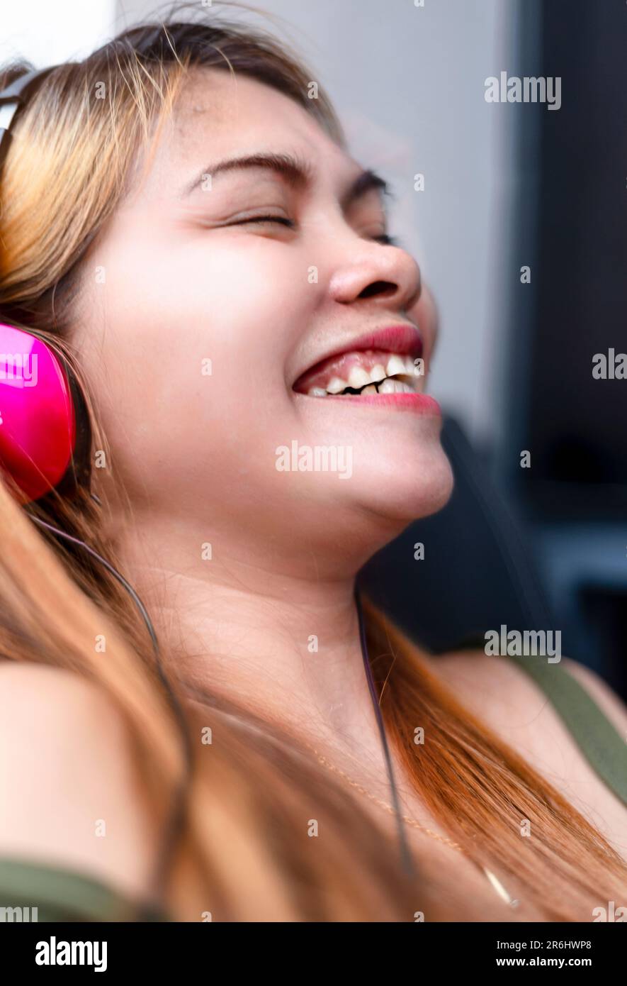 Sitting outside, on a modern high rise condo building balcony,wearing headphones,speaking long distance to her family who live in a remote part of rur Stock Photo