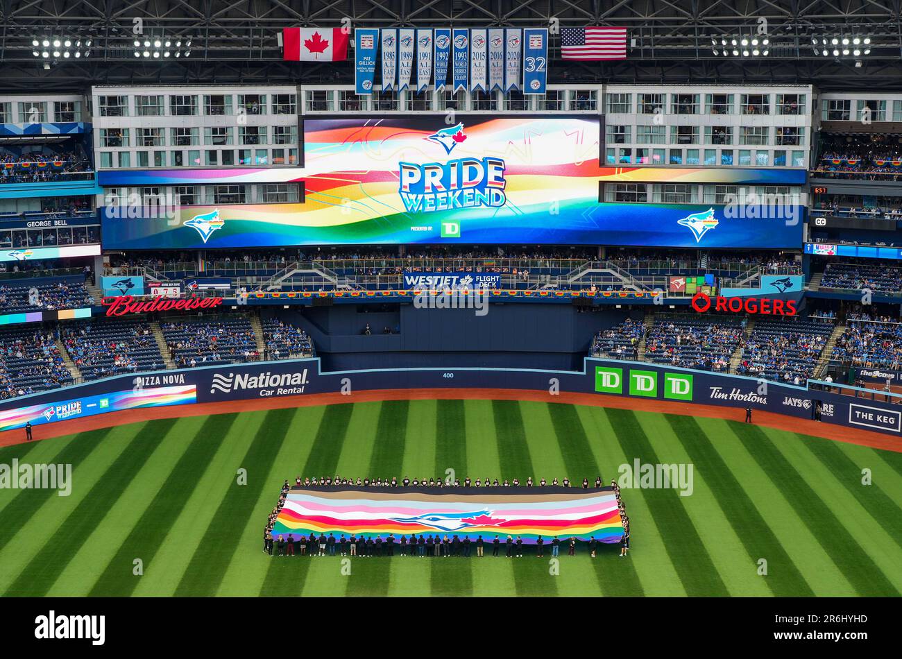 People hold a Pride-themed Toronto Blue Jays flag to celebrate Pride Weekend  before the team's baseball game against the Minnesota Twins on Friday, June  9, 2023, in Toronto. (Mark Blinch/The Canadian Press