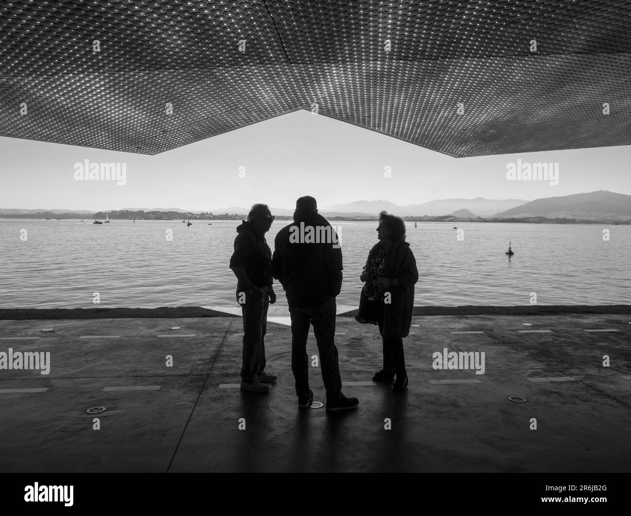 Silhouettes of people walking along a quay in the port of Santander ...