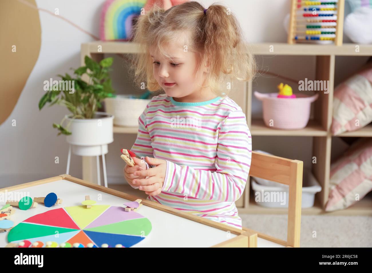 Cute little girl playing matching game with clothespins at home Stock