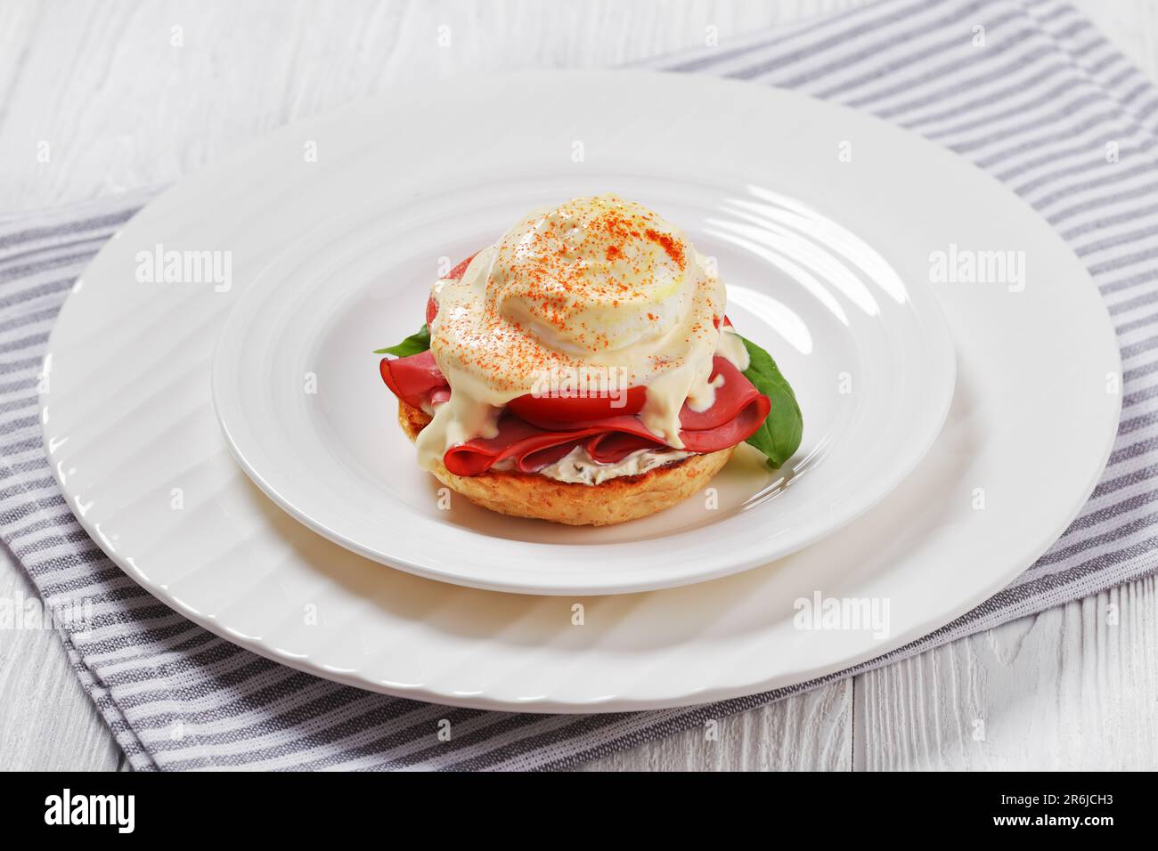 Egg Benedict with english muffin, soft cheese, ham, tomato, basil