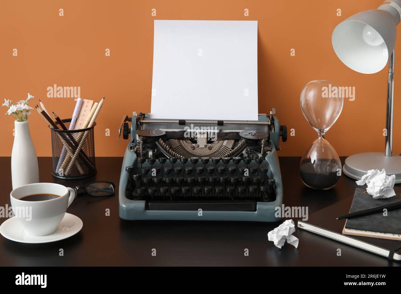 Vintage typewriter with cup of coffee, pencil holder and lamp on black ...