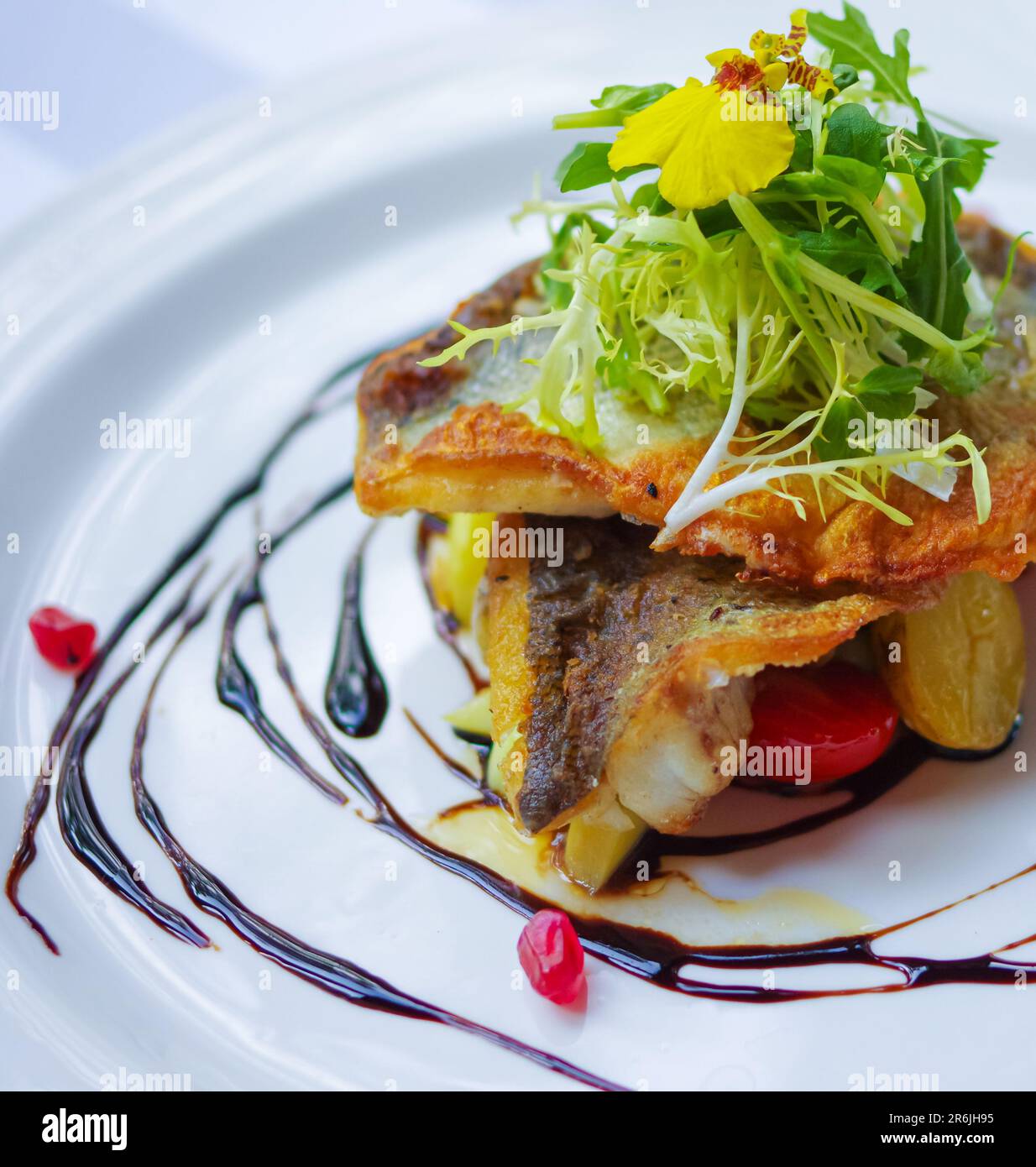 Crispy fried sea bass fillet with pomegranate seeds and balsamic