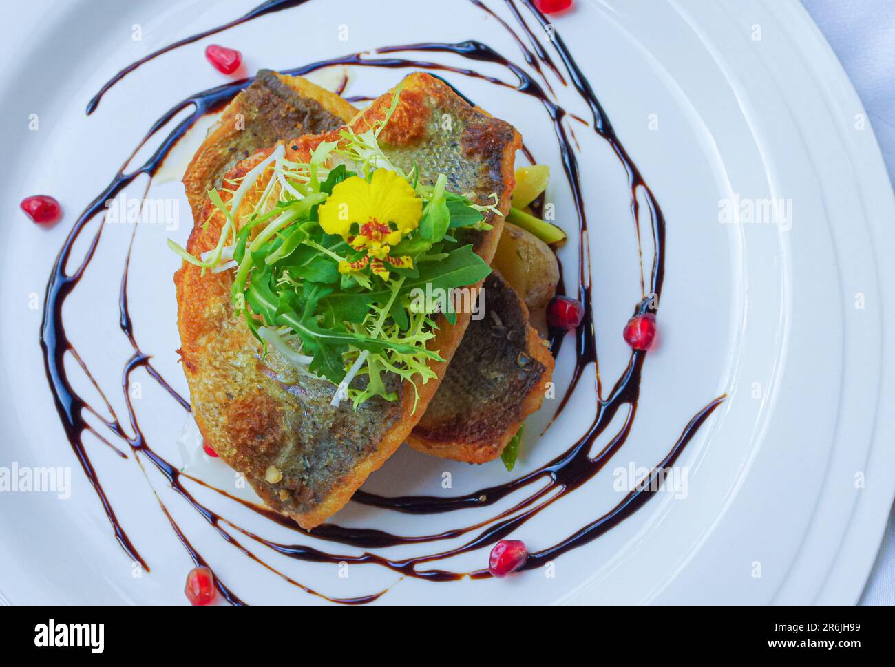 Crispy fried sea bass fillet with pomegranate seeds and balsamic