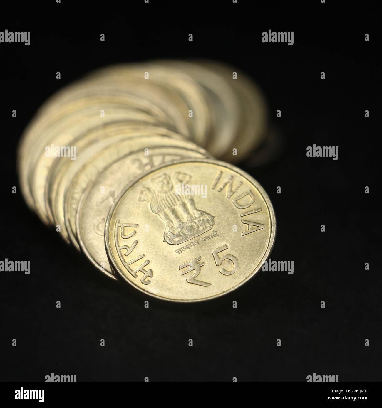 antique indian gold 5 (five) rupee coins arranged in a row shaped like a curve in closeup isolated in a black background Stock Photo