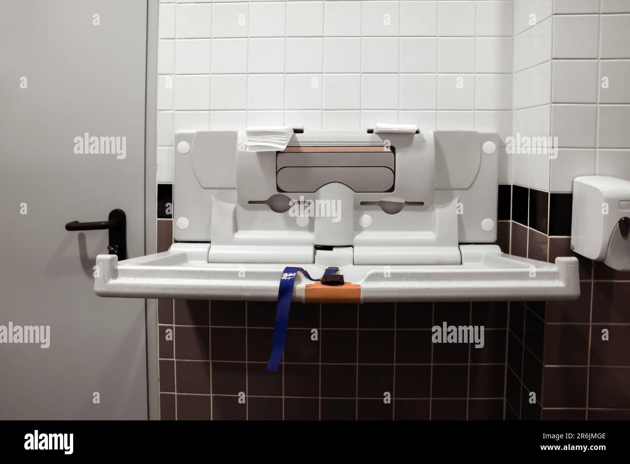 Modern baby changing table on tiled wall in public toilet Stock Photo