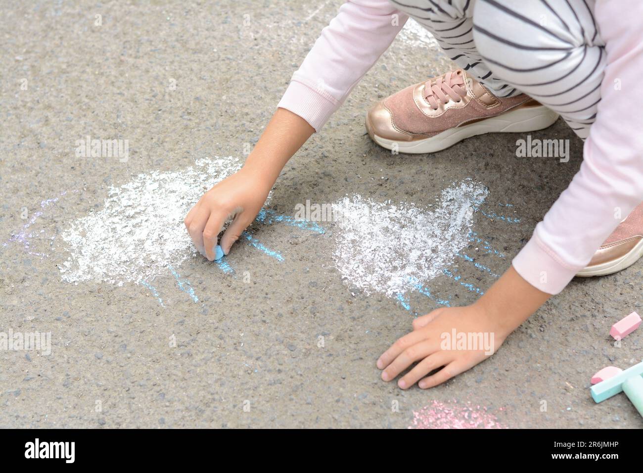 Little child drawing white clouds with chalk on asphalt, closeup Stock ...