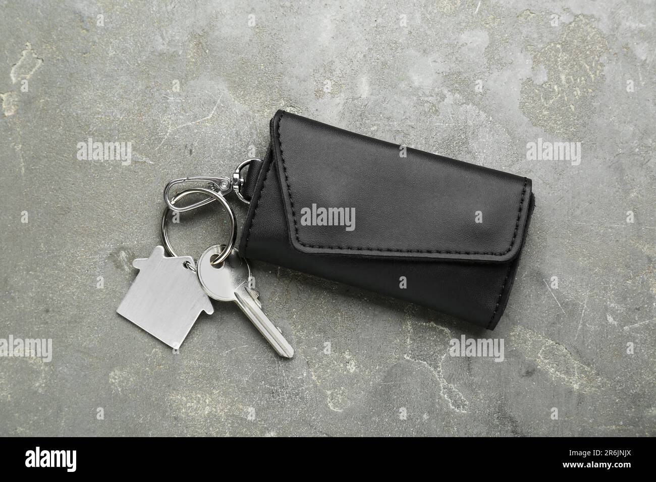 Leather case with key on grey textured table, top view. Stock Photo
