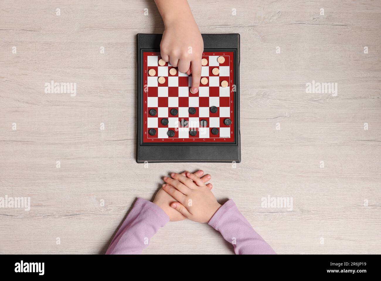 Children playing checkers at light wooden table, top view Stock Photo ...