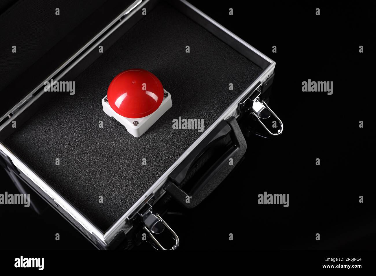 Red button of nuclear weapon in suitcase on black background, above view. War concept Stock Photo