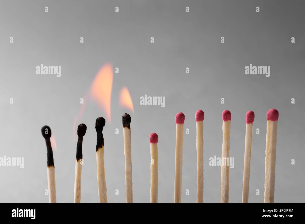 Burning and whole matches on light grey background, closeup. Stop