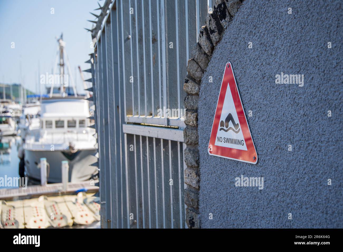No swimming sign by harbour with boats in the background Stock Photo