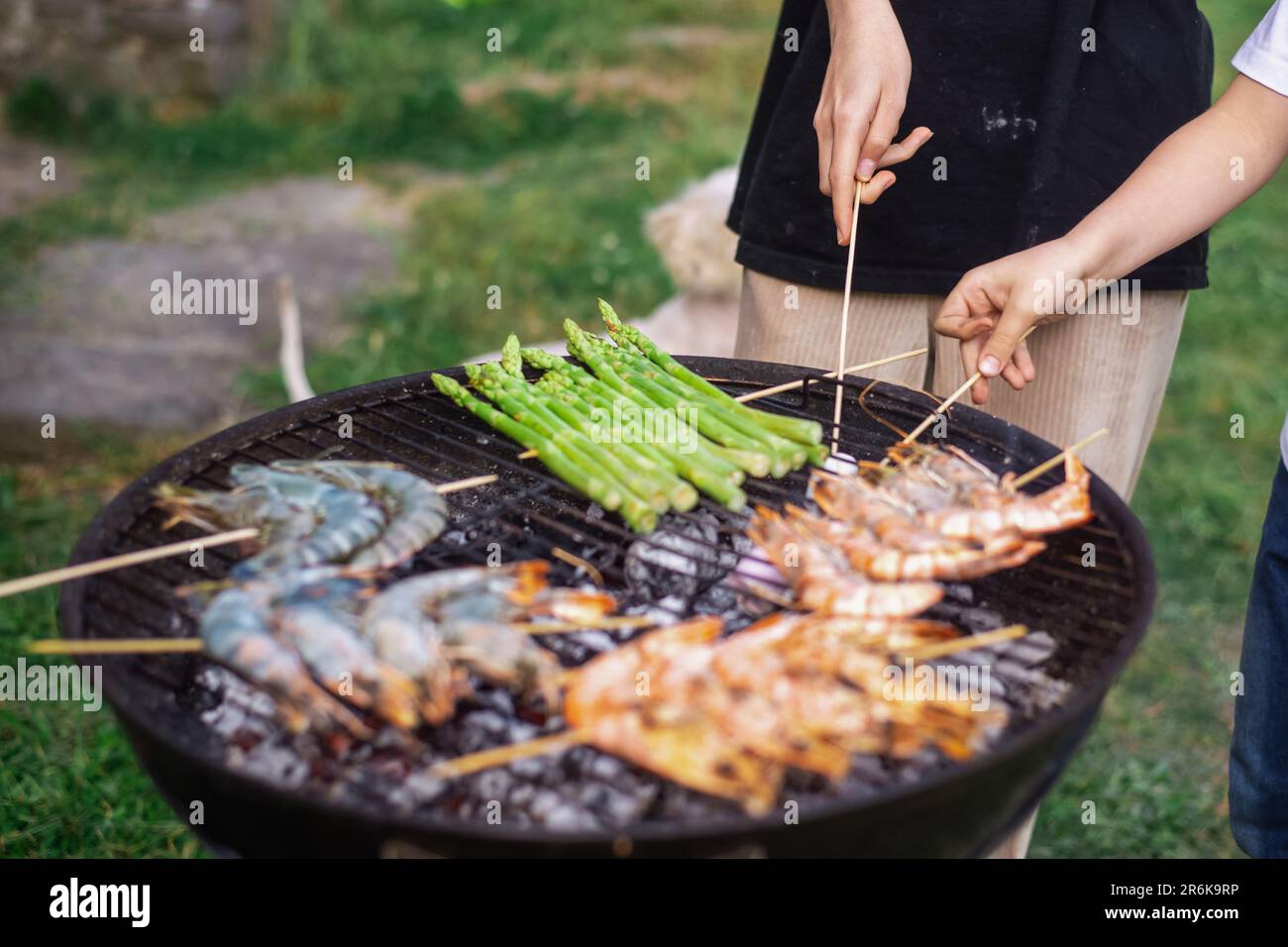 Round grill with king prawns and asparagus cooked on it. Stock Photo