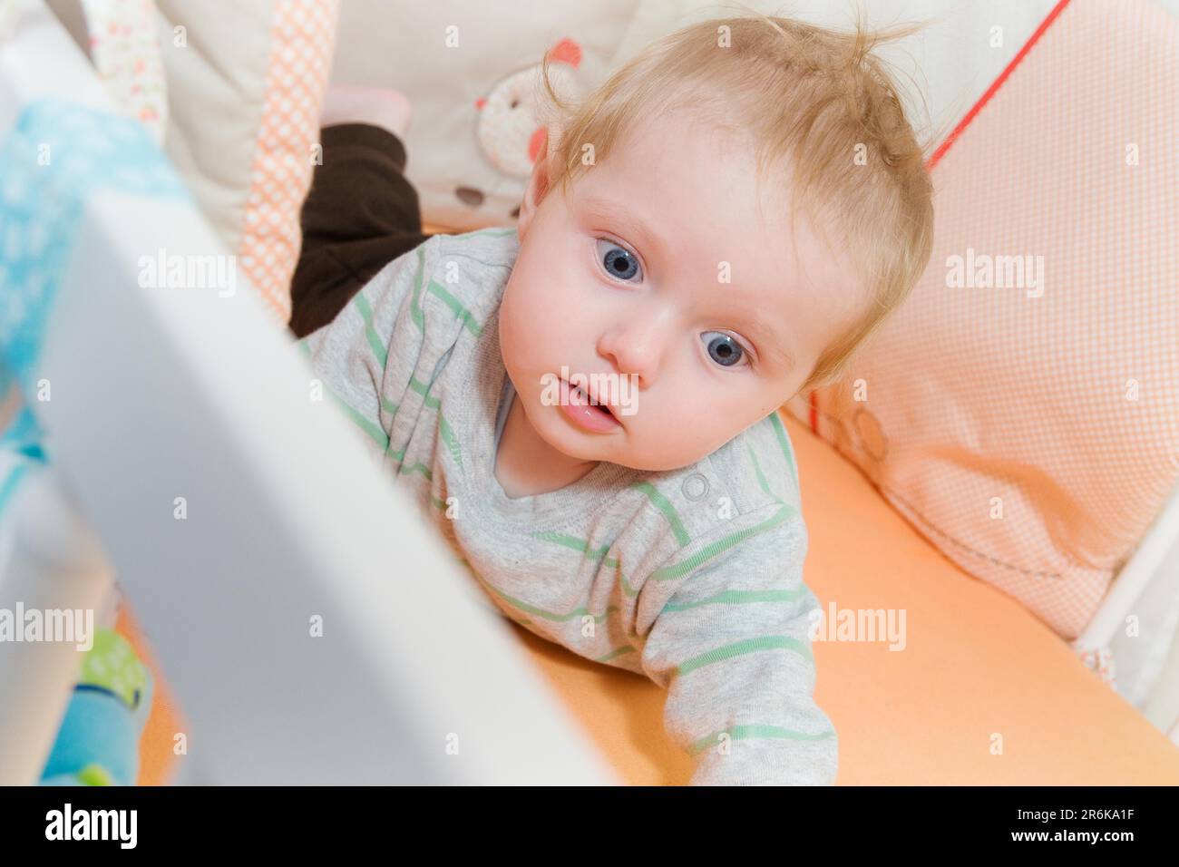 Toddler lies in the cosy cot and looks around Stock Photo Alamy