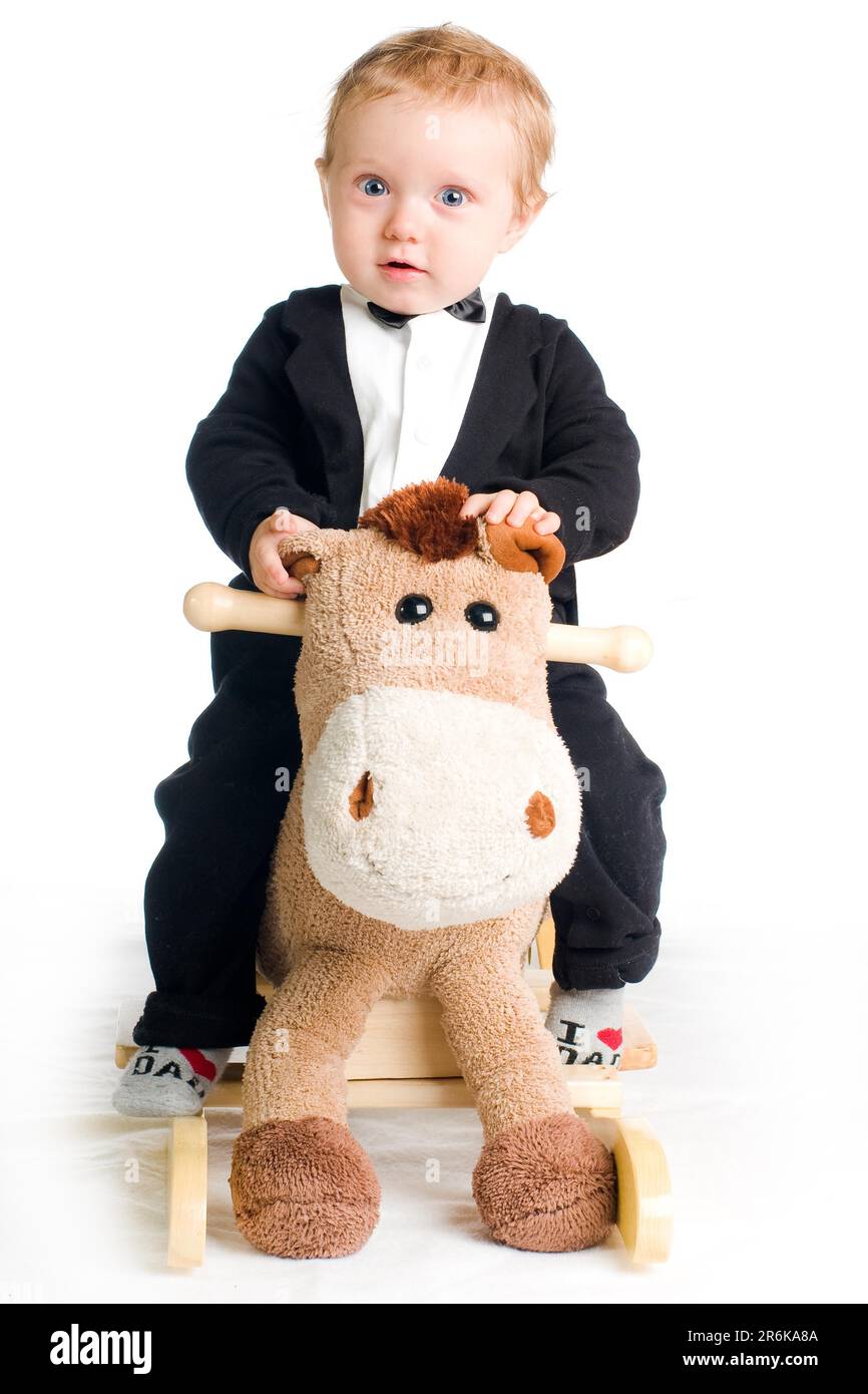 Chic cute kid in tails with bow tie on rocking horse Stock Photo