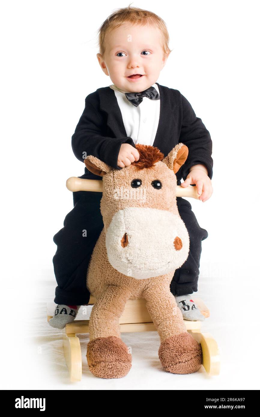 Chic cute kid in tails with bow tie on rocking horse Stock Photo