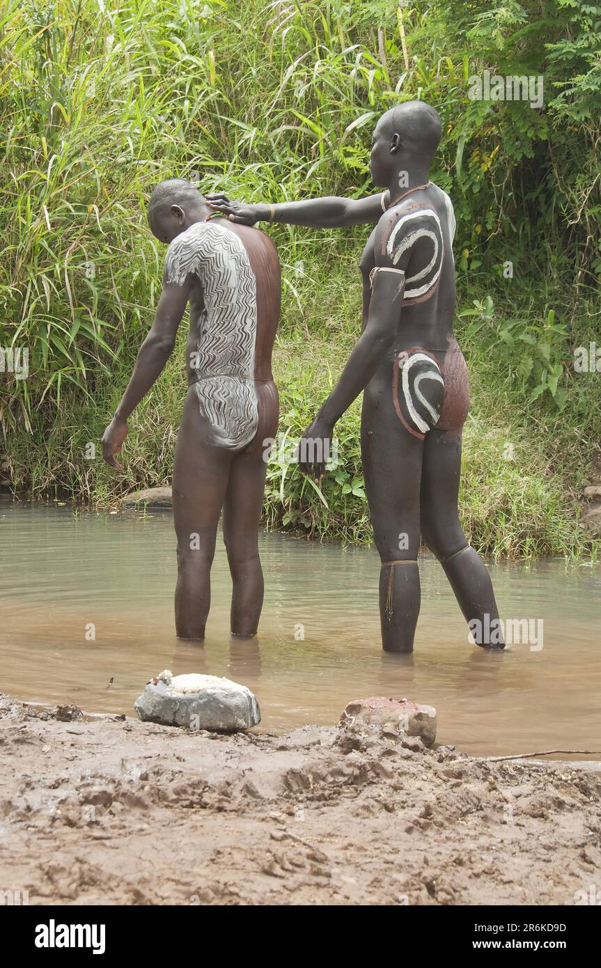 Surma man painting warrior's body, clay and mineral paint, in front of Donga stick fighting ceremony, Surma tribe, Tulgit, Omo Valley, Ethiopia Stock Photo