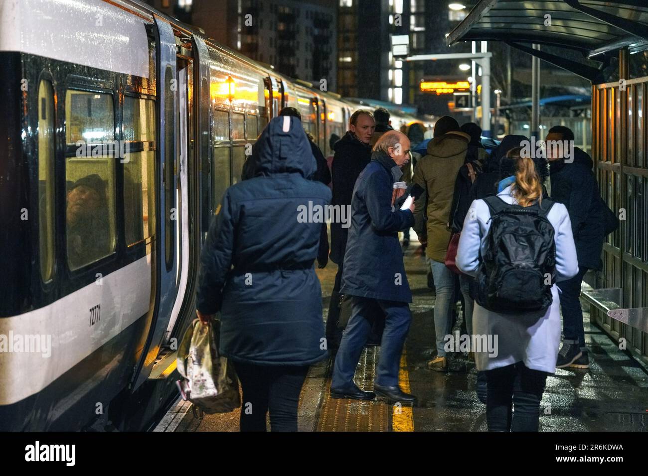 London, United Kingdom - February 01, 2019: Passengers getting on off National rail train at station platform at Lewisham during rainy cold evening Stock Photo