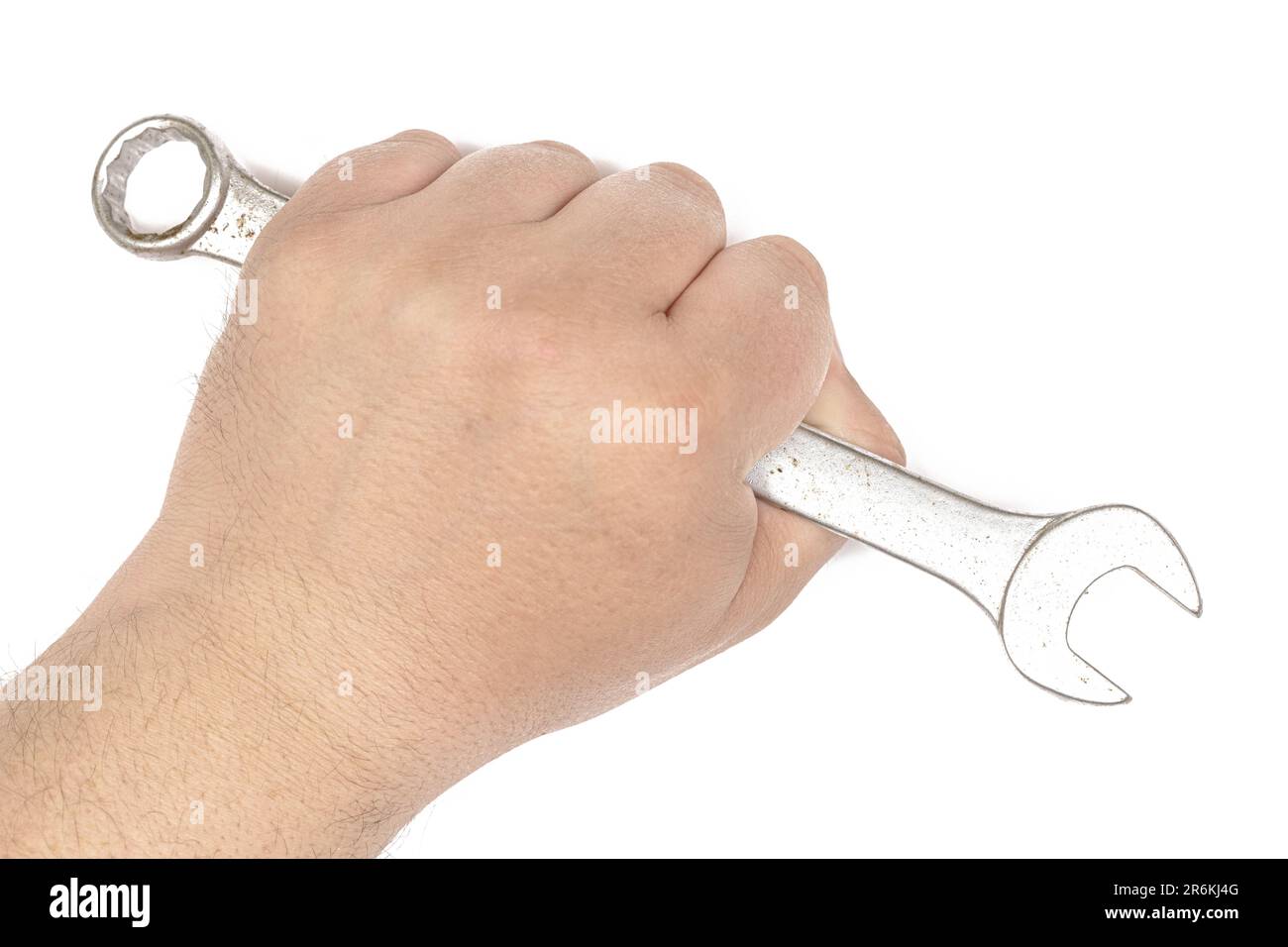 A close up image of a human hand gripping a metal wrench on a plain