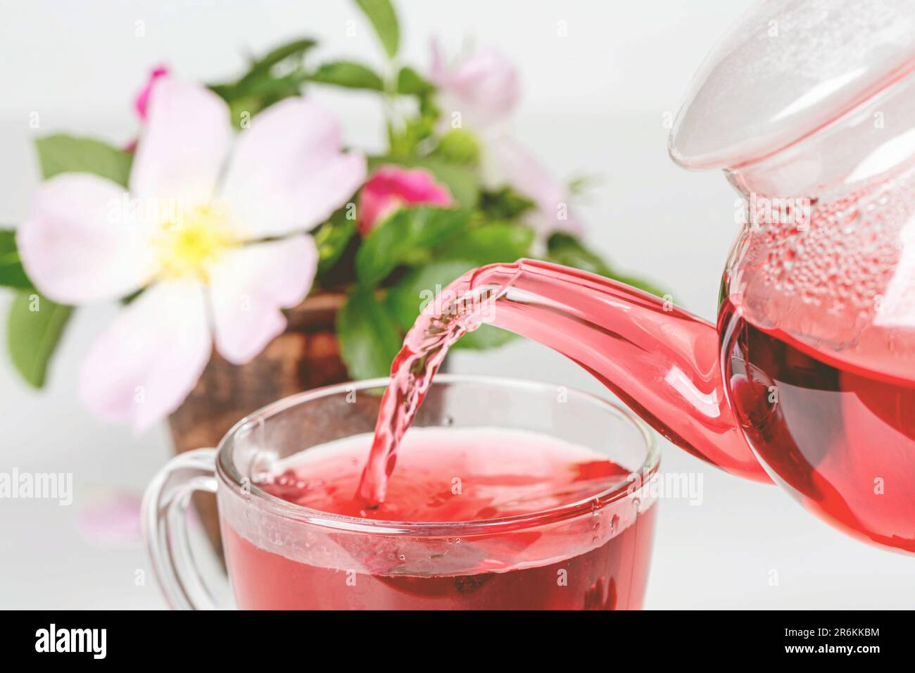 A white ceramic pitcher pouring liquid into a clear glass mug Stock ...