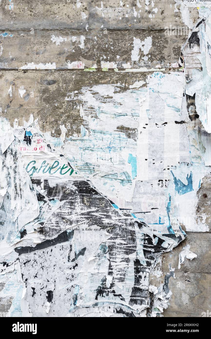 Concrete wall with colorful ripped bill posters. Grunge background Stock Photo