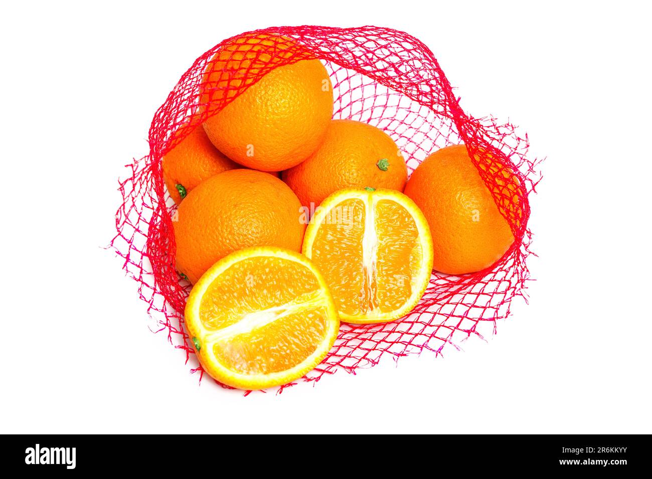 Fresh and juicy oranges in a red mesh bag isolated on white background. One orange is cut in half. Stock Photo