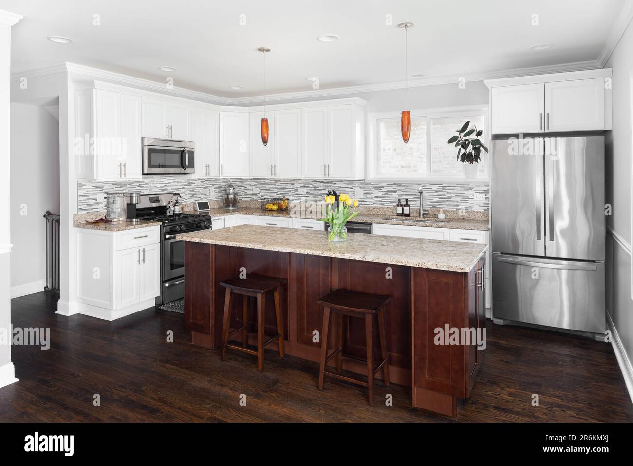 A kitchen with white cabinets, a large wood island, marble countertops ...