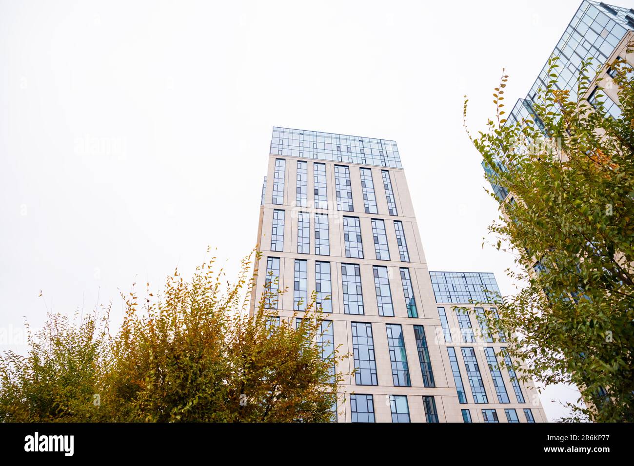 Blue beige modern apartment building, tree. Tile and glass facade. View