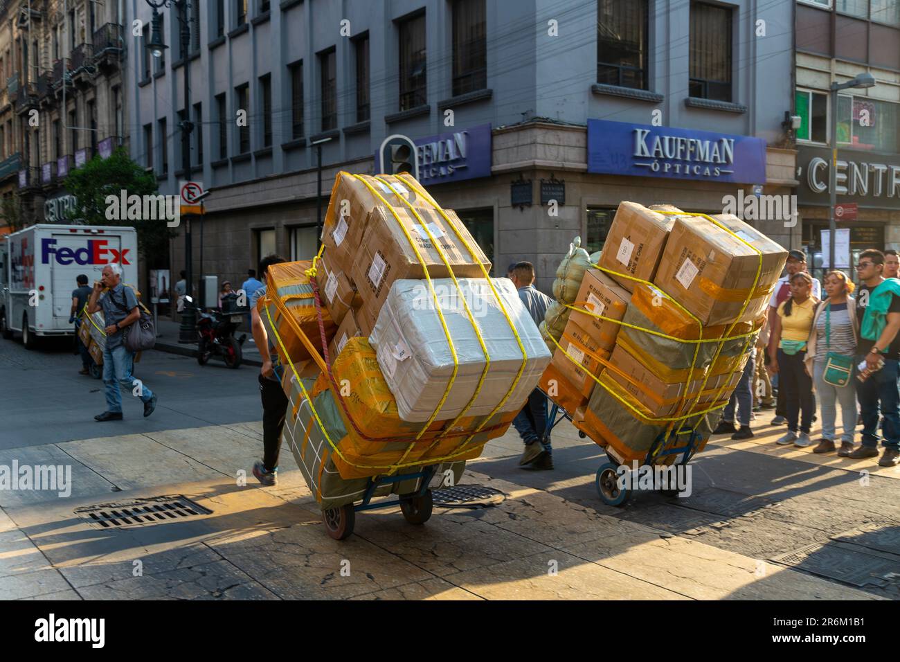 Men pulling carts loaded with large cardboard boxes, city centre Mexico