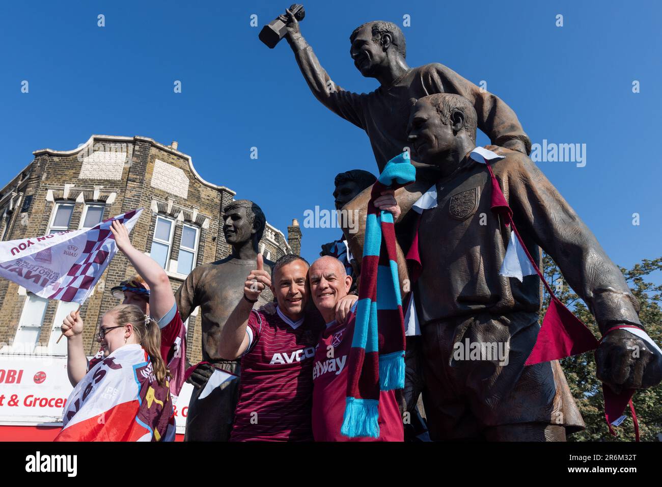 London, UK. 8th June, 2023. West Ham United supporters celebrate in front of The Champions sculpture close to the club's former Boleyn Ground stadium at Upton Park in advance of a UEFA Europa Conference League victory parade. West Ham defeated ACF Fiorentina in the UEFA Europa Conference League Final on 7 June, winning their first major trophy since 1980. Credit: Mark Kerrison/Alamy Live News Stock Photo